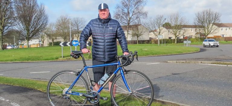 David with his bike standing where he was hit by a driver at a roundabout