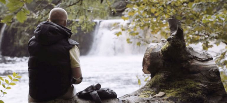 Client Ian McDonald who had his hand amputated sitting on log at a park in Glasgow